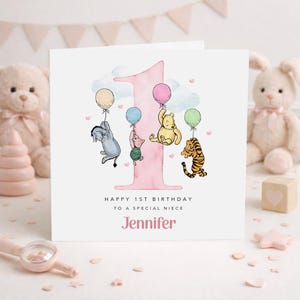 A personalized birthday card for a baby girl named Jennifer, featuring illustrations of Winnie the Pooh and other characters, along with balloons and a pink number one.