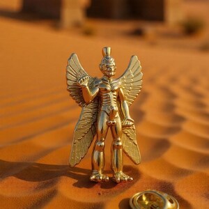 May include: A gold statue of a winged figure with a crown, set in a desert scene. The statue has detailed wings and is posed with one arm raised. A small, round, gold object is in front of the statue, in a sandy environment.