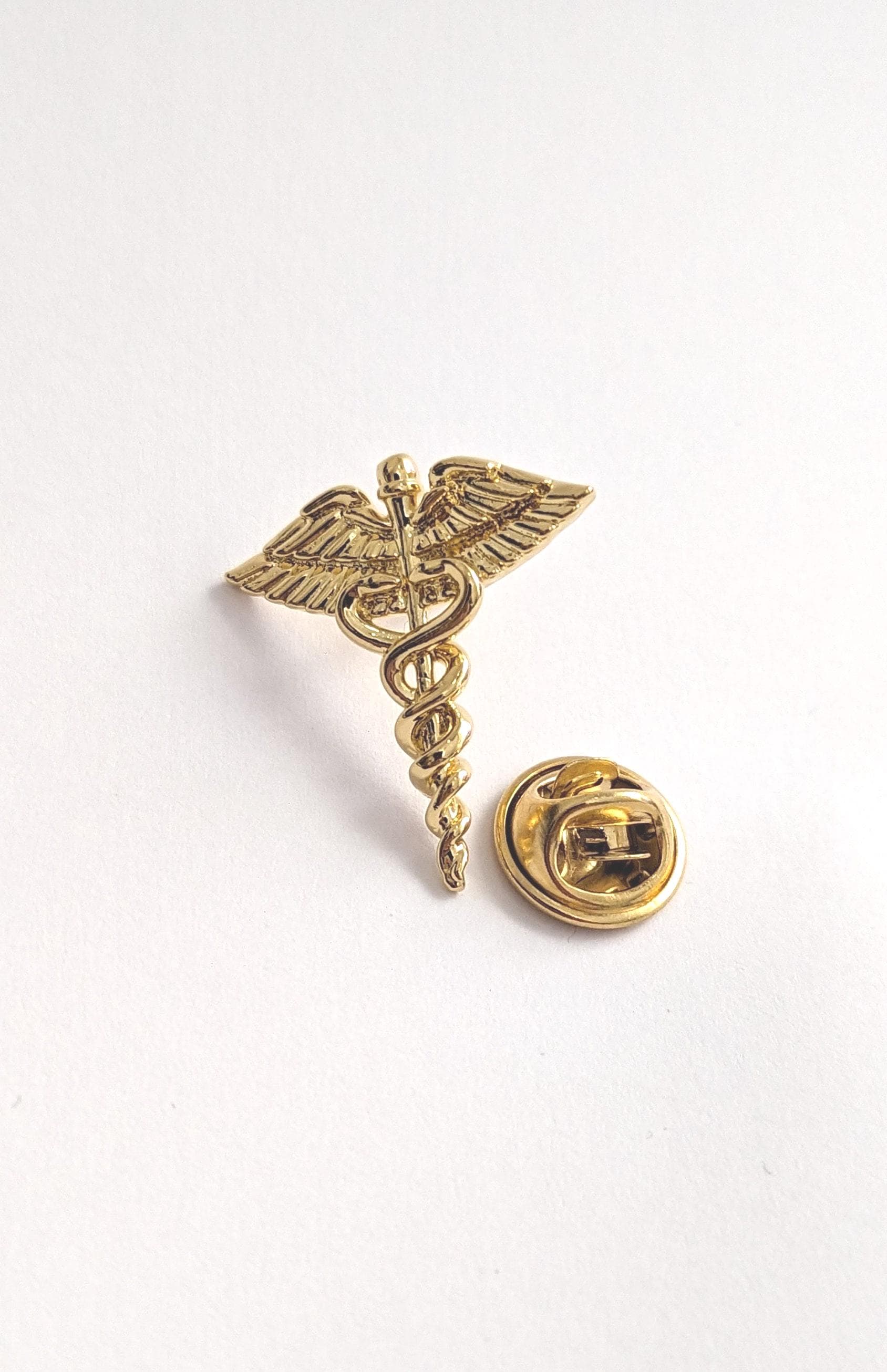 Medical Doctor Pin Caduceus. Classic medical symbol plated in gold. Elegance and meaning in a distinctive piece of jewelry.