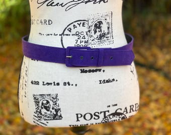 May include: A purple suede belt with a silver buckle. The belt is on a white mannequin with a vintage postcard design.