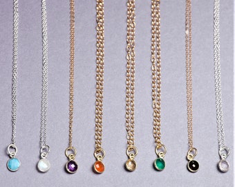 May include: Nine delicate necklaces with small gemstone pendants. The necklaces are silver and gold chains with turquoise, white, amethyst, carnelian, citrine, green, black, and white gemstones.