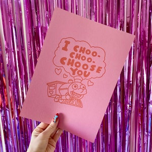 May include: Pink card with a cartoon train and the text "I choo-choo-choose you" in orange.