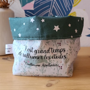 Peut inclure: Un panier de rangement en tissu avec un dessus vert à motifs d'étoiles et une base à imprimé floral. Le texte "Il est grand temps de rallumer les étoiles" est imprimé sur le devant. Le panier est sur une surface en bois.