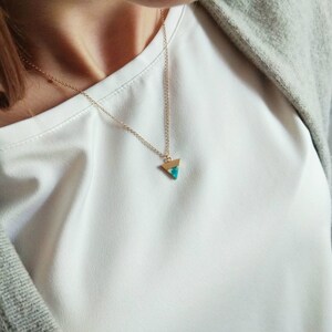 May include: A gold chain necklace with a turquoise triangle pendant.