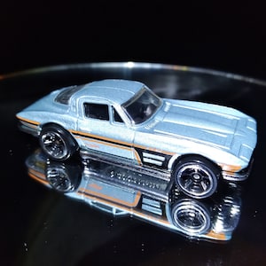 May include: A light blue toy car with black wheels and orange stripes. The car is a model of a classic Corvette.