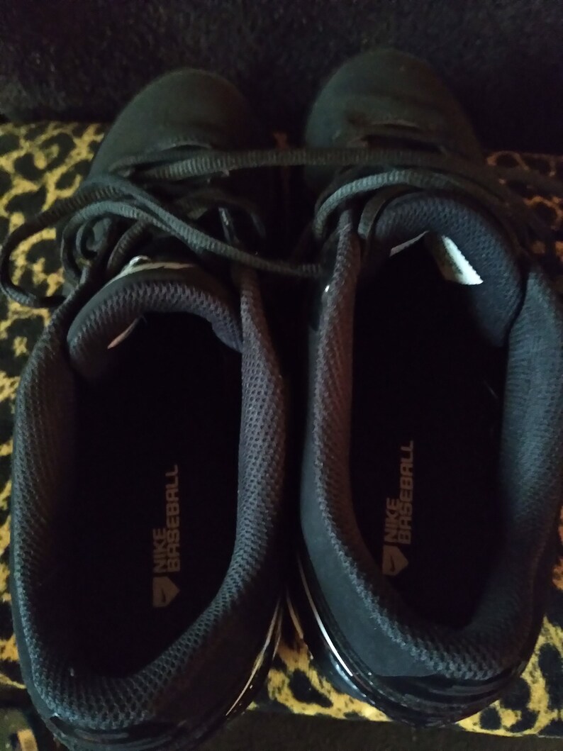 May include: A pair of black baseball cleats with white accents and the text "NIKE BASEBALL" on the inside of each shoe.