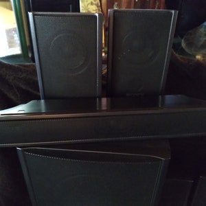 Puede incluir: Un sistema de sonido de cine en casa negro con una barra de sonido, dos altavoces sat&eacute;lite y un subwoofer. Los altavoces tienen una parte frontal de malla y la barra de sonido tiene la marca "Sony".