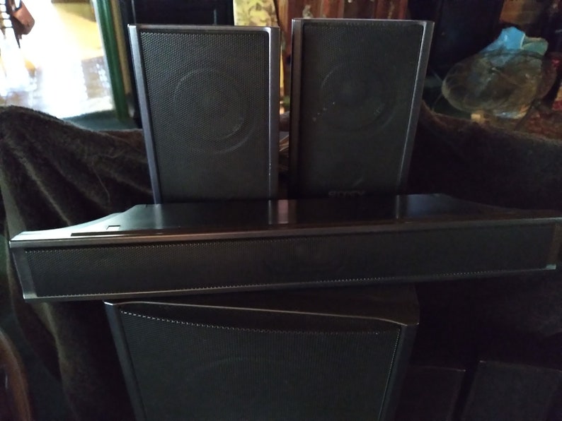 Puede incluir: Un sistema de sonido de cine en casa negro con una barra de sonido, dos altavoces sat&eacute;lite y un subwoofer. Los altavoces tienen una parte frontal de malla y la barra de sonido tiene la marca "Sony".