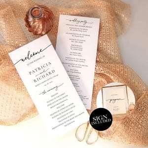 Puede incluir: Juego de papelería de boda con un letrero de bienvenida, detalles de la fiesta de bodas y un pequeño letrero enmarcado. Los artículos están sobre una tela texturizada de color dorado. También hay una botella de color cobre y unas tijeras doradas.