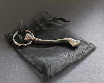 May include: A silver-colored key chain with a curved, smooth, and rounded design. The key chain is in a black velvet pouch.