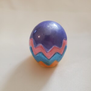 May include: A purple Easter egg with a pink, blue, and orange zigzag pattern.