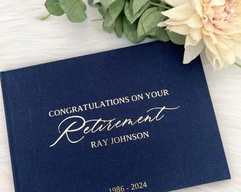 May include: A navy blue linen guest book with gold lettering that reads "Congratulations on your Retirement Ray Johnson 1986 - 2024".