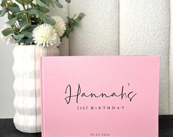 Könnte beinhalten: Ein rosa Gästebuch mit dem Namen "Hannah's" und "21ST BIRTHDAY" in Schreibschrift. Das Datum "30.05.2026" ist darunter aufgedruckt. Eine weiße Vase mit weißen Blumen und Grünzeug befindet sich im Hintergrund.