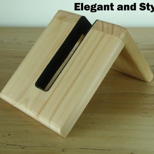 K&ouml;nnte beinhalten: Ein Holz-Telefonst&auml;nder mit einem schwarzen Filzeinsatz. Der St&auml;nder ist angewinkelt, um ein Telefon aufrecht zu halten. "Elegant and Stylish" steht in schwarzer Schrift oben im Bild.