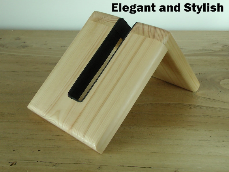 K&ouml;nnte beinhalten: Ein Holz-Telefonst&auml;nder mit einem schwarzen Filzeinsatz. Der St&auml;nder ist angewinkelt, um ein Telefon aufrecht zu halten. "Elegant and Stylish" steht in schwarzer Schrift oben im Bild.