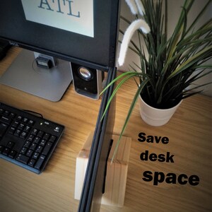 K&ouml;nnte beinhalten: Ein Laptopst&auml;nder aus Holz mit einem Laptop darauf. Der St&auml;nder steht auf einem Holztisch mit einer Tastatur, einem Computermonitor und einer Topfpflanze. Der Text "Save desk space" ist auf dem Tisch geschrieben.