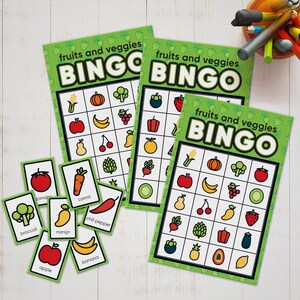 May include: Three green bingo cards with the text "fruits and veggies BINGO" on each card. The cards have a grid of 25 squares with different fruits and vegetables in each square. There are also 10 small cards with pictures of different fruits and vegetables.