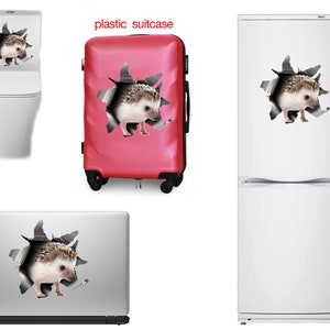 May include: A set of stickers with a hedgehog design, applied to a toilet, a red suitcase, a fridge, and a laptop. Each sticker depicts a hedgehog seemingly breaking through a torn hole in the surface.