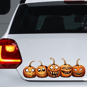 以下が含まれることがあります： 異なる不気味な顔をした、オレンジ色のハロウィーンかぼちゃのステッカーが5つ並んでいます。ステッカーは白い車の後ろにあります。