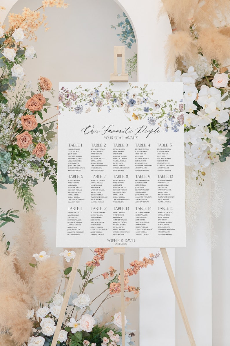 May include: A wedding seating chart with a floral design. The chart lists the names of guests assigned to each table. The text at the top reads "Our Favorite People Your Seat Awaits".