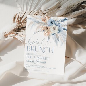 May include: A blue and white bridal brunch invitation with a watercolor floral design. The invitation includes the text "bridal brunch", "Please join us in honor of the bride-to-be", "Olivia Robert", "Saturday 25 December 20xx", "Two o'clock in the afternoon", "At this location - 123 Anywhere St. Any City, ST 12345", and "RSVP on or before November 15th at 123-456-7890".
