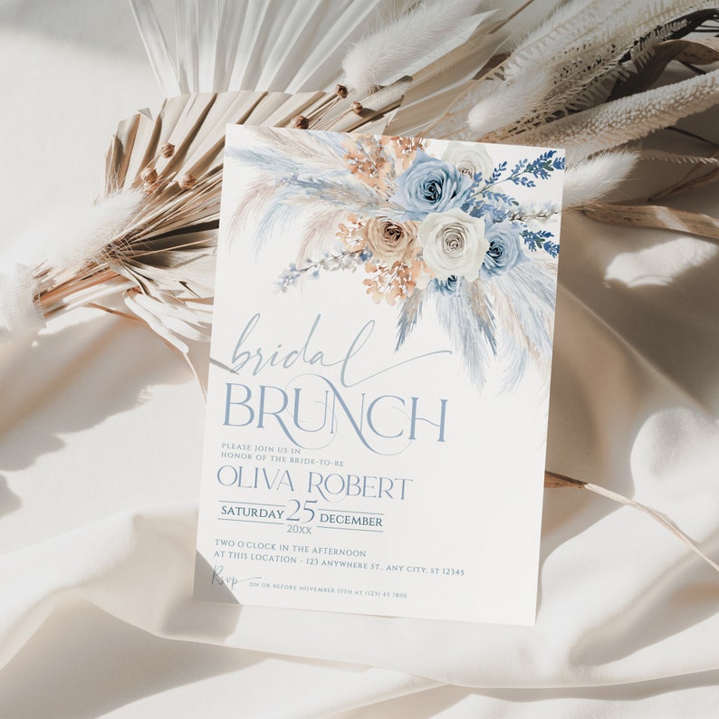 May include: A blue and white bridal brunch invitation with a watercolor floral design. The invitation includes the text "bridal brunch", "Please join us in honor of the bride-to-be", "Olivia Robert", "Saturday 25 December 20xx", "Two o'clock in the afternoon", "At this location - 123 Anywhere St. Any City, ST 12345", and "RSVP on or before November 15th at 123-456-7890".