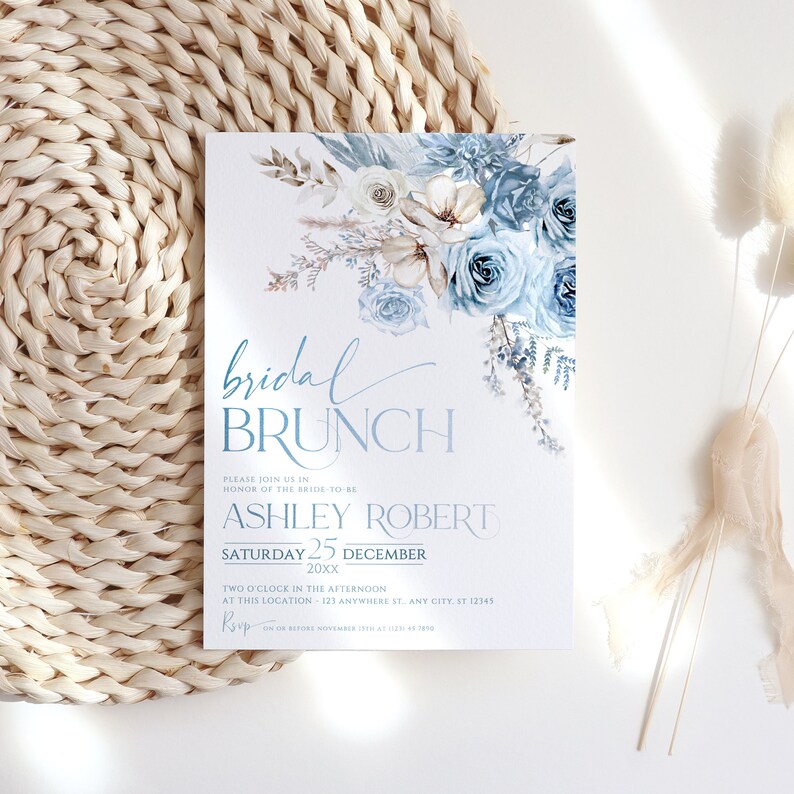 May include: A blue and white floral bridal brunch invitation with the text "bridal brunch" in a blue and white script font. The invitation includes the bride-to-be's name, the date, and the time of the event. RSVP information is included at the bottom of the invitation.