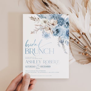 May include: A blue and white bridal brunch invitation with watercolor floral designs. The invitation reads "bridal brunch" and includes the bride-to-be's name, the date, and the time of the event. RSVP information is also included.