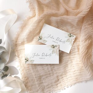 May include: Two white place cards with a watercolor floral design and the text "Julia Roberts, Table 01".
