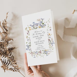 May include: A wedding ceremony program with a floral border. The text reads "Welcome to the Wedding of Sophie Anne Jurner and David Ryan Branson, Sunday, 27th July, 20XX, At this location."