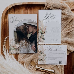 Puede incluir: Un juego de invitaciones de boda con una foto de pareja, una nota de regalo y una tarjeta de detalles. Las tarjetas est&aacute;n decoradas con ilustraciones de hierba de la pampa y arcos. Un sello de cera dorado y un sello de lat&oacute;n sobre madera.