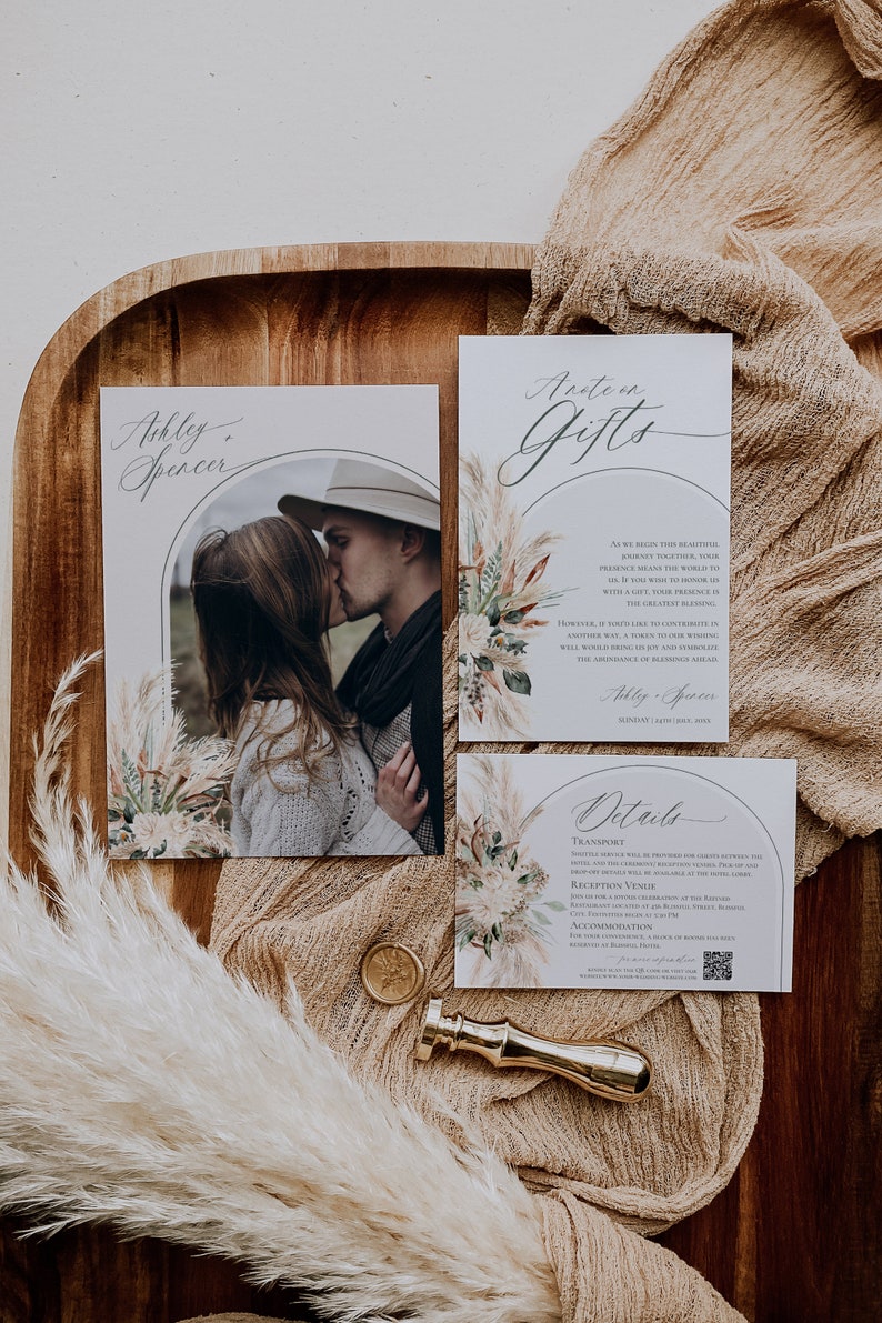 Puede incluir: Un juego de invitaciones de boda con una foto de pareja, una nota de regalo y una tarjeta de detalles. Las tarjetas est&aacute;n decoradas con ilustraciones de hierba de la pampa y arcos. Un sello de cera dorado y un sello de lat&oacute;n sobre madera.