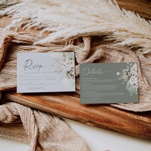 May include: Two rectangular wedding stationery cards featuring floral illustrations. The left card is light gray with the text RSVP, while the right card is sage green with the text Details. Both cards include printed event information.