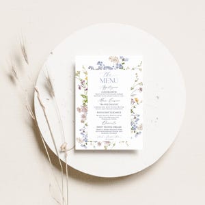 Puede incluir: Un men&uacute; de papel rectangular con un delicado borde floral de acuarela en tonos azules, rosas y amarillos. El texto dice: The Menu, Appetizers, Luxe Sea Bites, Main Course, Truffle Delight, Indulgent Elegance, Desserts, Sweet Truffle Dreams.