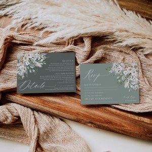 May include: A gray and white wedding RSVP card with a floral design. The card has the text "Roop" in cursive and includes a section for guest names, dietary requirements, and a space for the guest to sign their name.