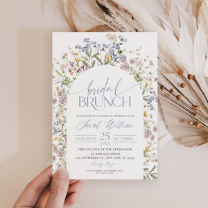 Pu&ograve; includere: Un invito per un brunch nuziale con le parole "bridal BRUNCH" in elegante scrittura. L'invito include dettagli come il nome della sposa, la data, l'ora e il luogo, circondato da un delicato bordo floreale.