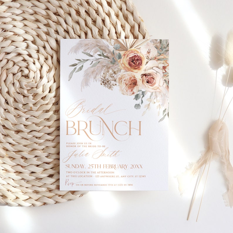 May include: A rectangular invitation card featuring a floral arrangement of pampas grass and roses in shades of peach and cream. The text reads Bridal BRUNCH, Julia Smith, Sunday 25th February 20XX, and includes RSVP details.