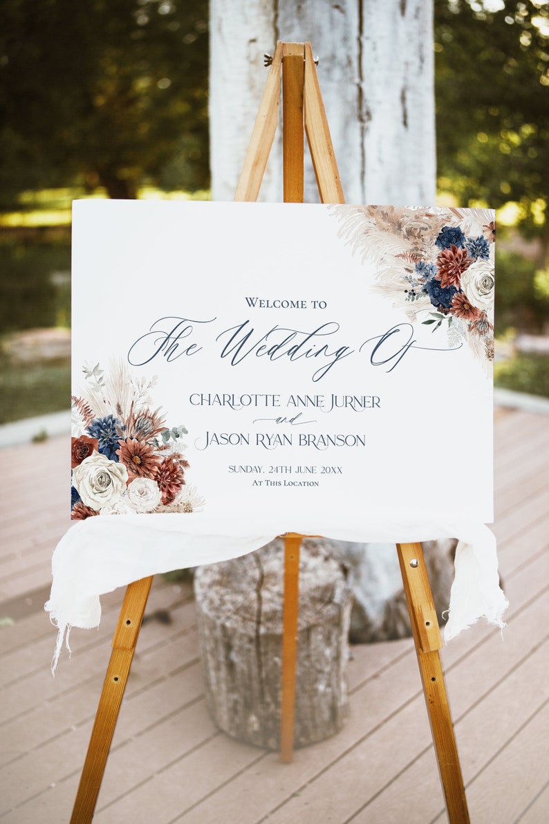 May include: Welcome to The Wedding Of Charlotte Anne Jurner and Jason Ryan Branson, Sunday, 24th June 20XX, at this location. A white sign with blue and red floral design.