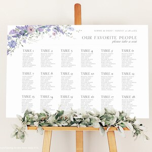 Puede incluir: Un plano de asientos de boda con un dise&ntilde;o floral en tonos morados y blancos. El gr&aacute;fico est&aacute; titulado "Nuestra gente favorita" y enumera las mesas con los nombres de los invitados.