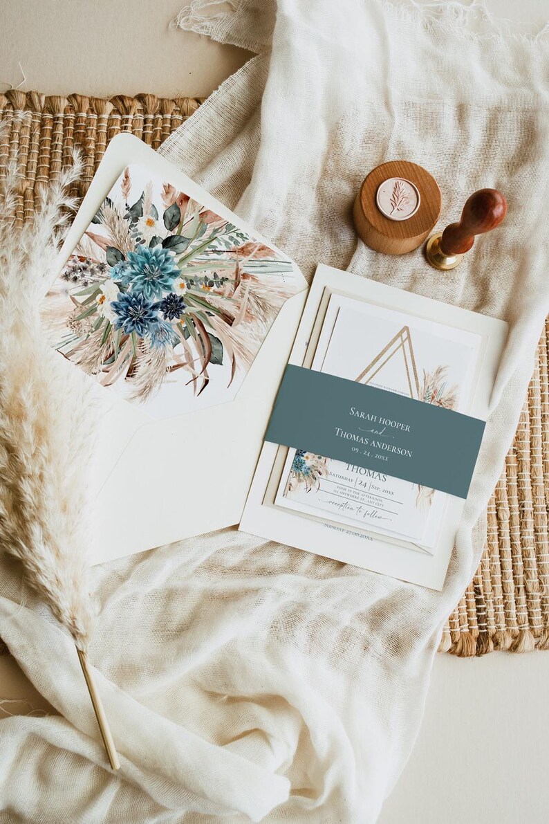 Puede incluir: Juego de invitaciones de boda con un dise&ntilde;o floral en tonos azules y beige. La invitaci&oacute;n incluye los nombres "Sarah Hooper y Thomas Anderson" y la fecha "09.24.2023". Tambi&eacute;n hay un sello de madera con un dise&ntilde;o floral.