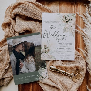 May include: A wedding invitation set featuring a photo card of a couple and a details card with floral accents, text reading The Wedding of Jessica Hooper and Richard Anderson, and a gold wax seal stamp on a wooden board with tan fabric.