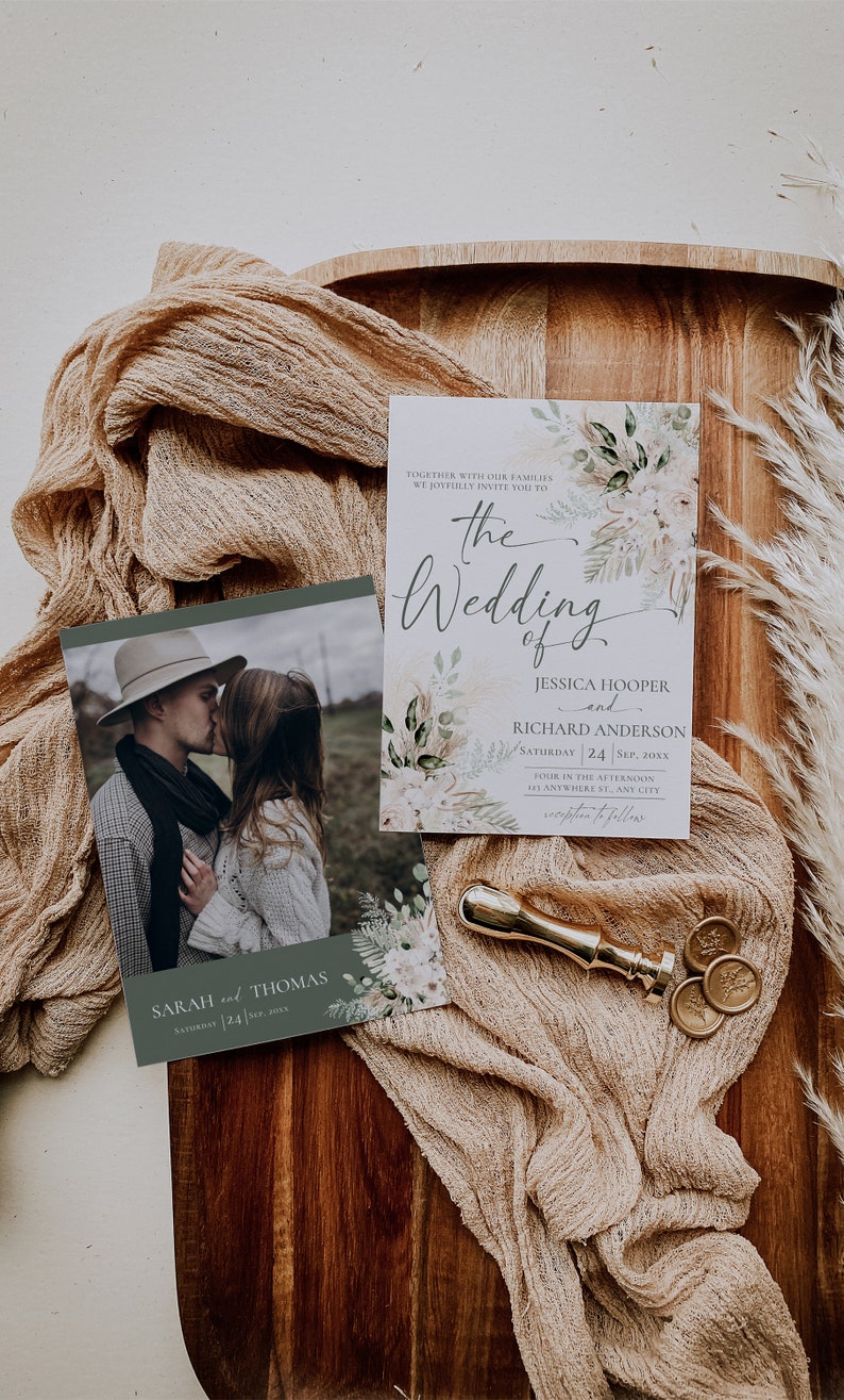 May include: A wedding invitation set featuring a photo card of a couple and a details card with floral accents, text reading The Wedding of Jessica Hooper and Richard Anderson, and a gold wax seal stamp on a wooden board with tan fabric.