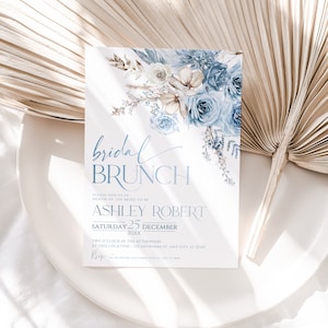 May include: A blue and white floral bridal brunch invitation with the text "bridal brunch" in a script font. The invitation includes the bride-to-be's name, the date, and the time of the event. RSVP information is included at the bottom of the invitation.