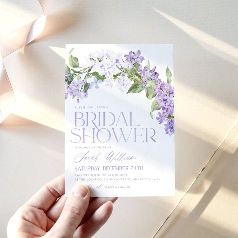 May include: A bridal shower invitation with a watercolor illustration of purple flowers. The text on the invitation reads 'Please join us for a Bridal Shower in honor of the bride Sarah William Saturday, December 24th Two o'clock in the afternoon at this location, 123 Anywhere St., Any City, ST 12345  Target & Amazon'