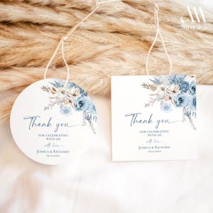 Pu&ograve; includere: Due etichette regalo in carta bianca, una circolare e una quadrata, con un'illustrazione floreale blu ad acquerello in alto. Il testo recita Thank you FOR CELEBRATING WITH US with love JESSICA & RICHARD 09.25.20XX. Ogni etichetta ha un cordino bianco.
