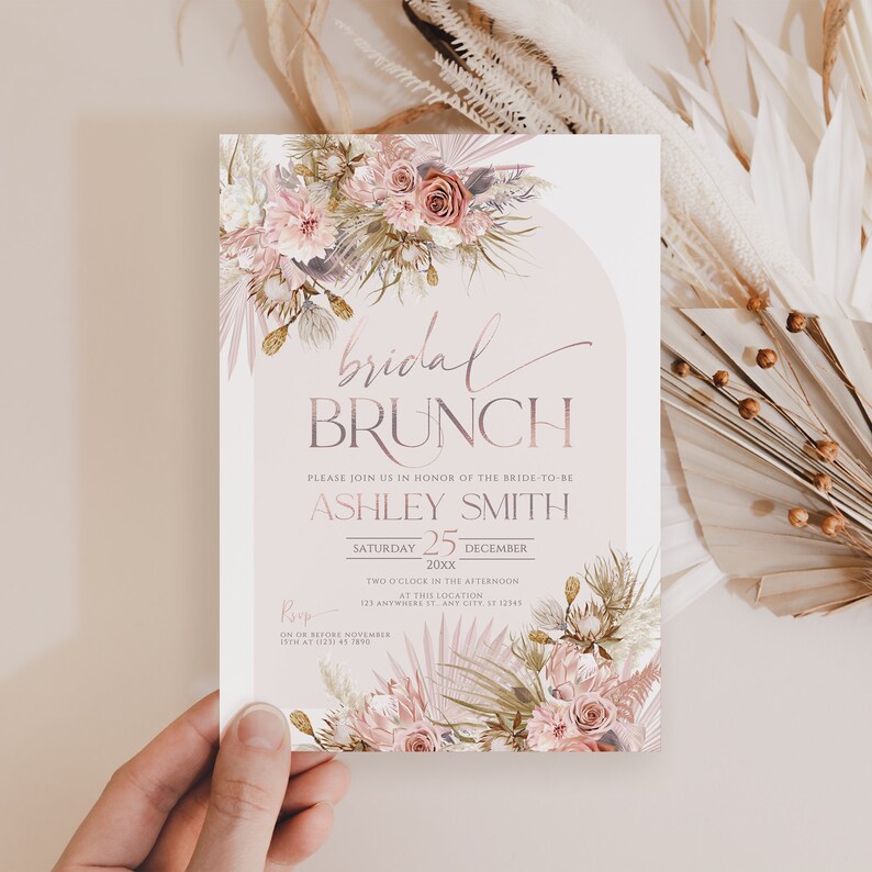 May include: A blush pink and white floral bridal brunch invitation with a gold and white RSVP card. The invitation features the text "bridal brunch" and "Ashley Smith" with a date of December 25th.