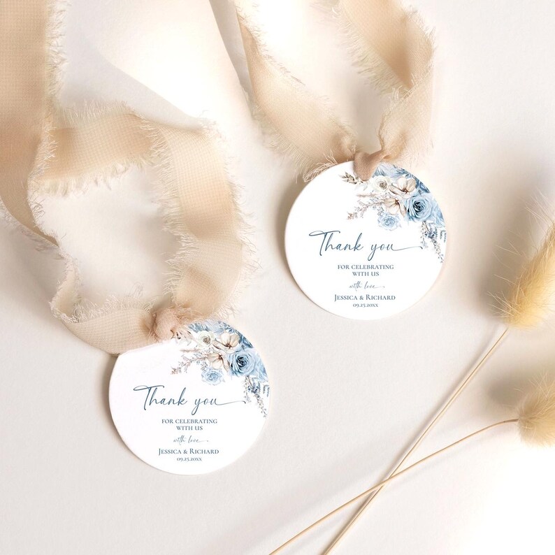 Pu&ograve; includere: Due etichette regalo rotonde bianche con un'illustrazione floreale blu ad acquerello nella parte superiore. Il testo recita Thank you FOR CELEBRATING WITH US with love JESSICA & RICHARD 09.25.20XX. Ogni etichetta &egrave; fissata a un nastro di seta beige sfilacciato.