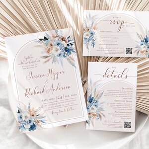 May include: A wedding invitation suite featuring a main invitation, an RSVP card, and a details card. Each white card displays an arched frame, blue and beige floral arrangements, and elegant script text including names and event details.