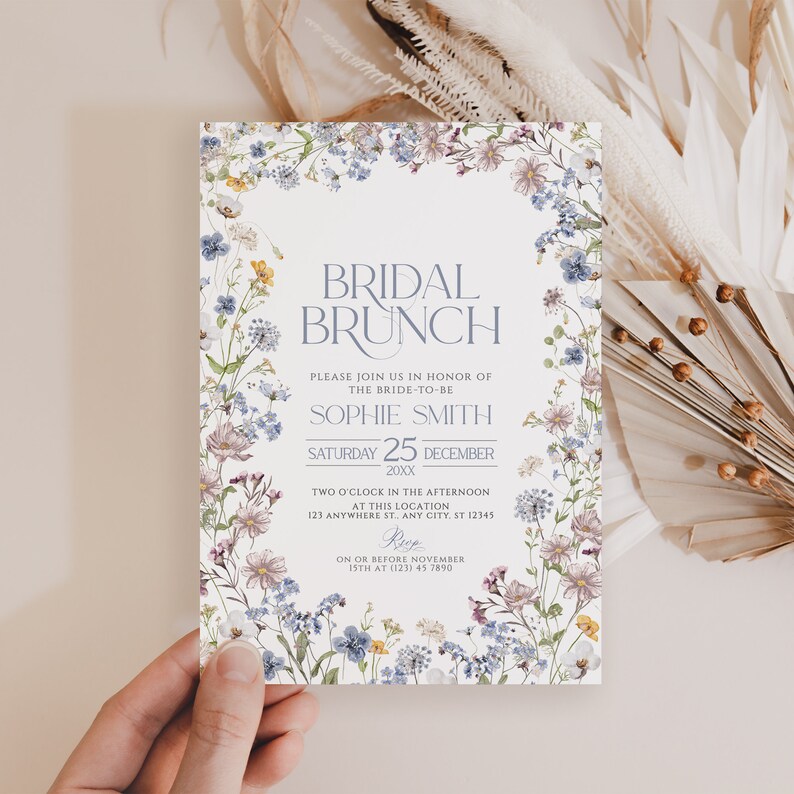 May include: A floral bridal brunch invitation with a white background and a border of watercolor flowers in shades of blue, pink, and yellow. The text reads "Bridal Brunch" in a blue font, followed by the bride-to-be's name, "Sophie Smith", the date, "Saturday 25 December 20XX", and the time and location of the event.