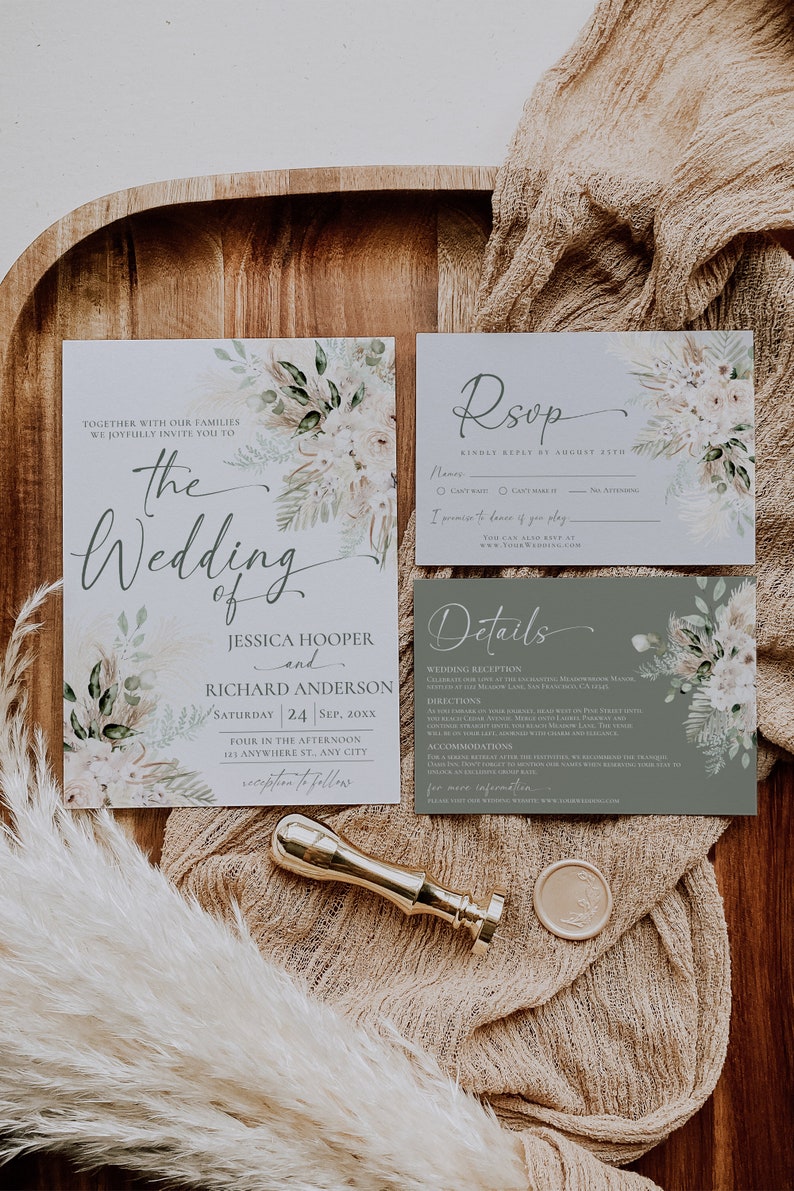 May include: A wedding invitation suite featuring a main invitation, an RSVP card, and a details card, all decorated with floral and pampas grass illustrations. A gold wax seal stamp and a circular wax seal are placed alongside the stationery.